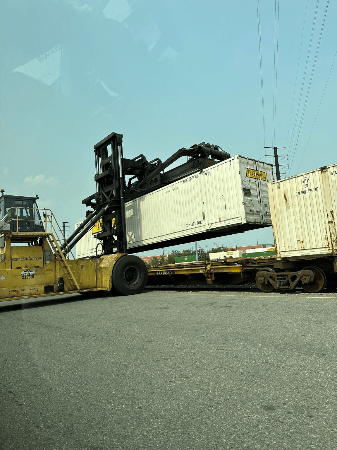 A container handler lifting a shipping container onto a railcar at an intermodal terminal